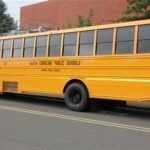 Image of Durham Public Schools buses lined up outside a school, highlighting the bus service cuts and transportation issues facing local families.